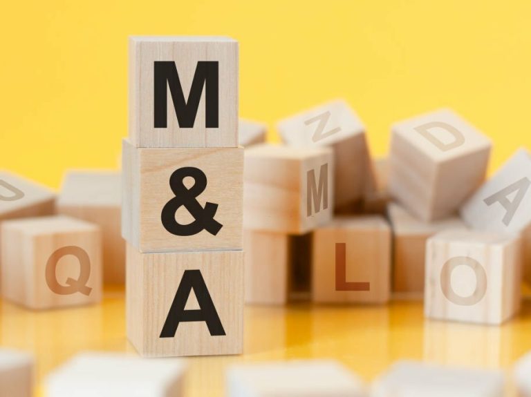 M and A - short for mergers and acquisitions - written on a wooden cube, business concept. yellow bacground. can be used for business, marketing, education, financial concept. Selective focus.